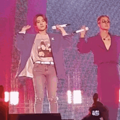a couple of people are standing on a stage holding microphones .