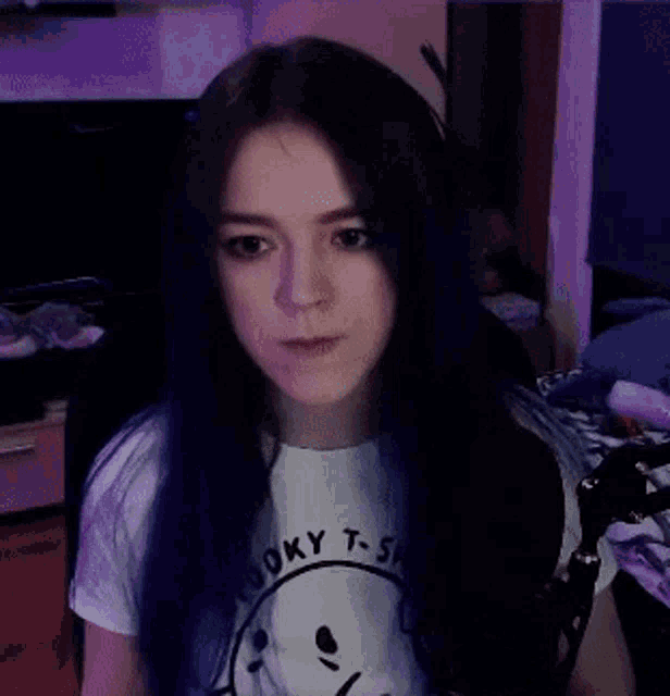 a woman with blue hair is wearing a white t-shirt with a smiley face on it
