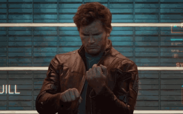 a man in a leather jacket is giving the middle finger in front of a wall that says " devil "