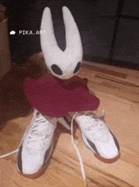 a stuffed animal is sitting on top of a pair of shoes .