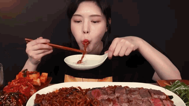 a woman is eating a large plate of food with chopsticks and a spoon