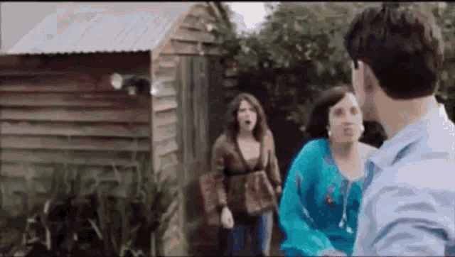 a man and two women are standing in front of a shed .