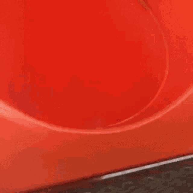 a little girl is sitting in a red slide and smiling .