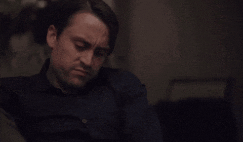 a man in a blue shirt is sitting in a chair with his head down .