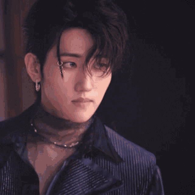 a close up of a man wearing a choker necklace and earrings .