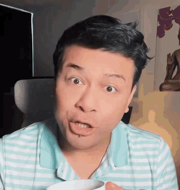 a man in a striped shirt is making a funny face with his mouth open