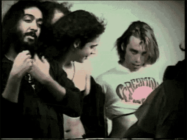 a man in a creamo shirt stands in a crowd