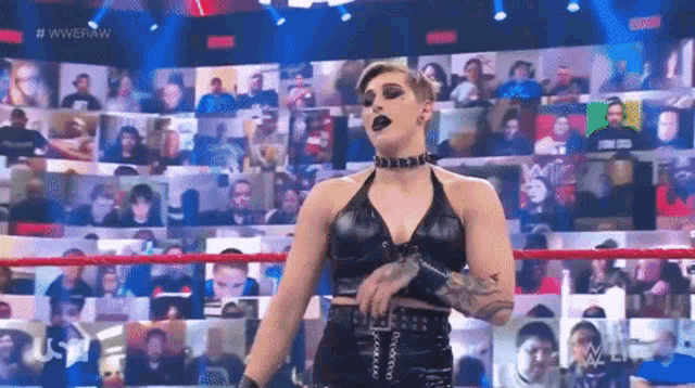 a woman is standing in a wrestling ring with a crowd watching .