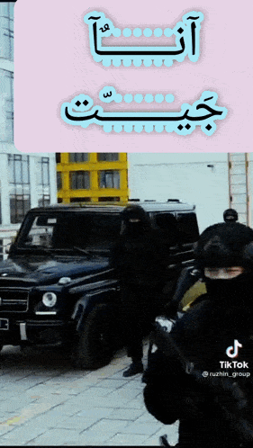 a group of people standing in front of a black car with arabic writing on it