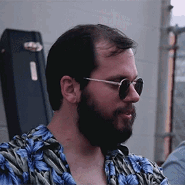 a man with a beard wearing sunglasses and a shirt with blue flowers