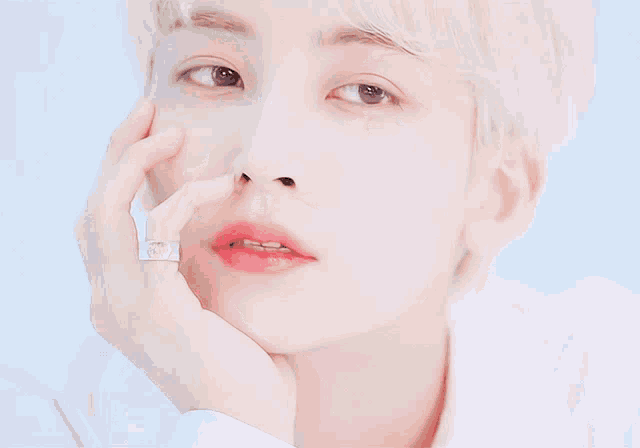 a close up of a person 's face with a ring on his finger