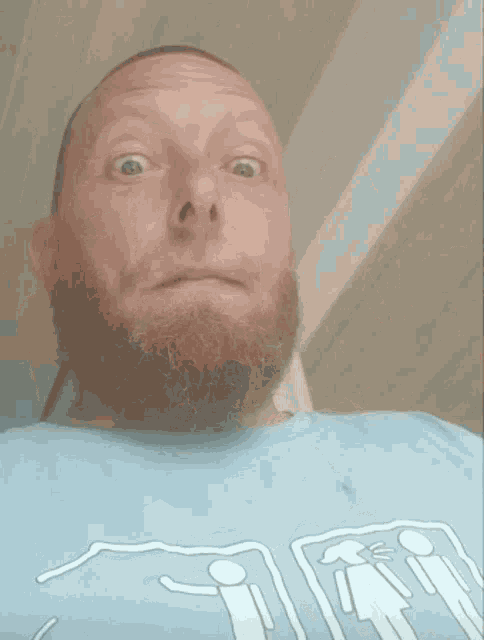 a man with a beard is wearing a blue t-shirt with drawings of people on it