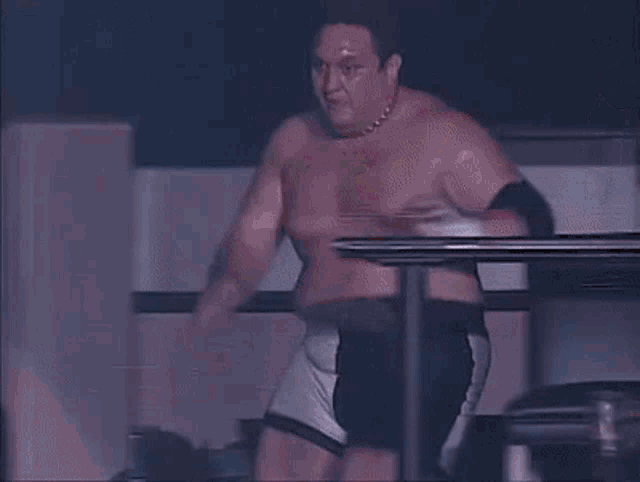 a man without a shirt is in a boxing ring with a referee in the background
