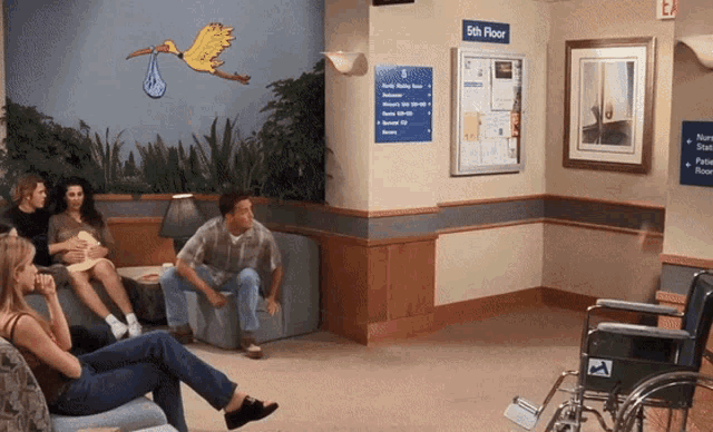 a group of people sitting in a waiting room with a wheelchair