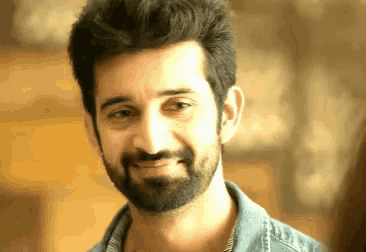 a man with a beard and a blue shirt smiles
