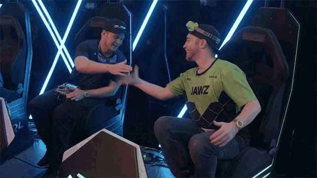 a man wearing a jawz shirt shakes the hand of another man