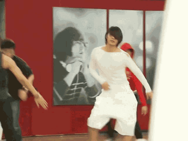 a man in a white shirt is dancing in front of a painting
