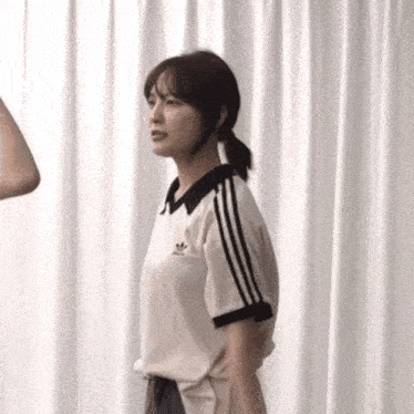 a woman wearing a white adidas shirt with black stripes