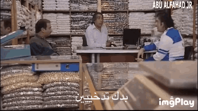 a man sitting at a desk in a store with abu alfahad jr written on the bottom of the screen