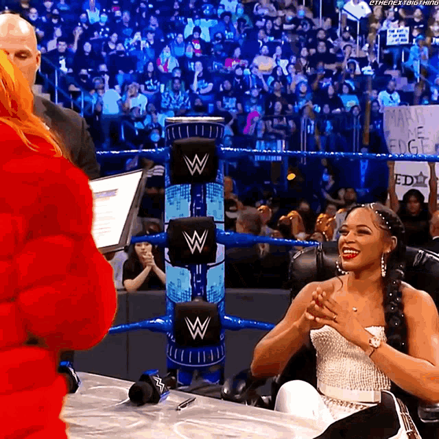 a woman sitting in front of a wrestling ring with a sign that says marvin the flight
