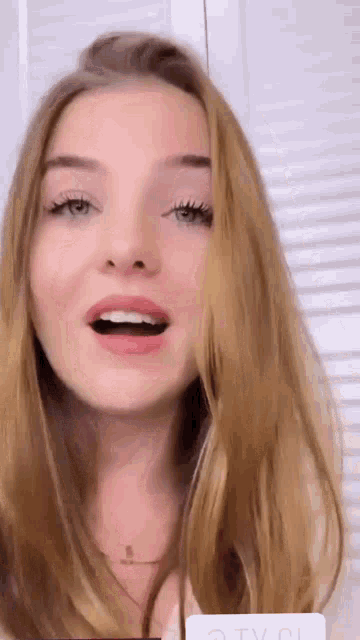 a close up of a woman 's face with her mouth open and her hair blowing in the wind .