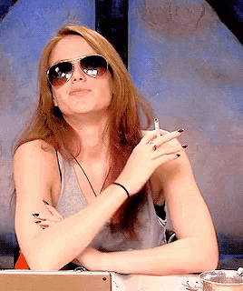 a woman wearing sunglasses and a tank top is smoking a cigarette