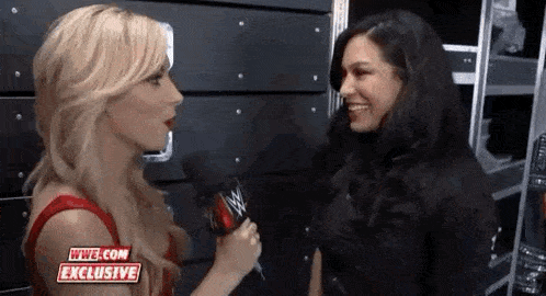 two women are talking to each other in a room while holding microphones .