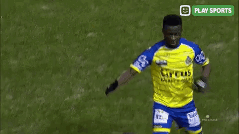 a soccer player wearing a yellow and blue jersey with the word circus on it is talking to a man on the field .
