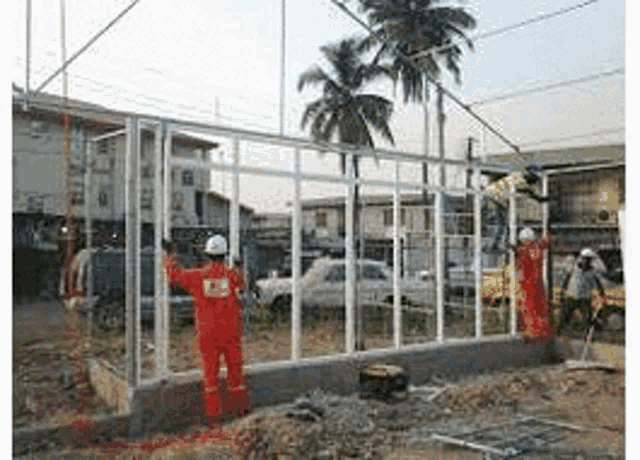 a group of construction workers are working on a building in a field .