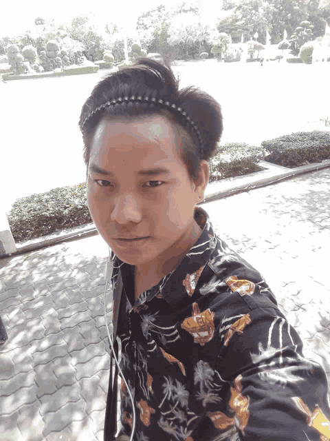 a young man wearing a headband and a floral shirt