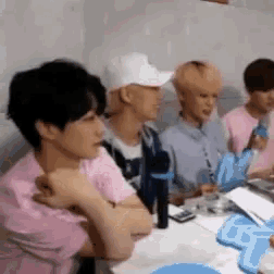 a group of young men are sitting at a table with microphones in front of them .