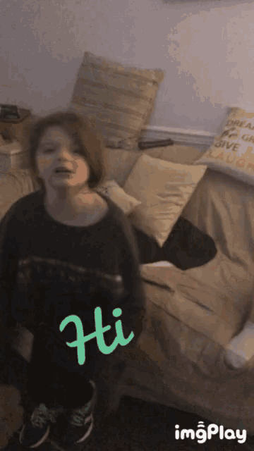 a little girl is standing in front of a couch with the word hi written on it