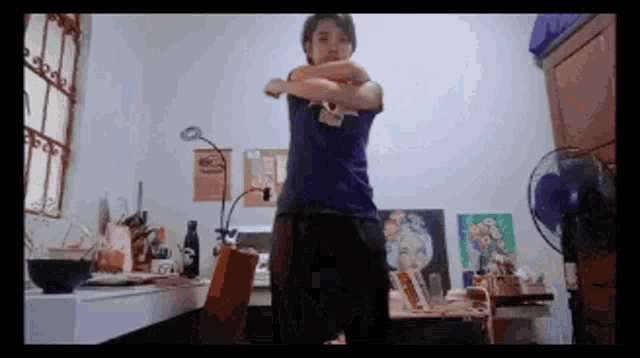 a person in a room with a fan and a painting on the wall that says ' a ' on it