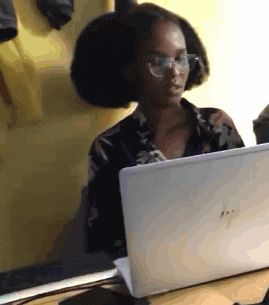 a woman wearing glasses is sitting in front of a hp laptop
