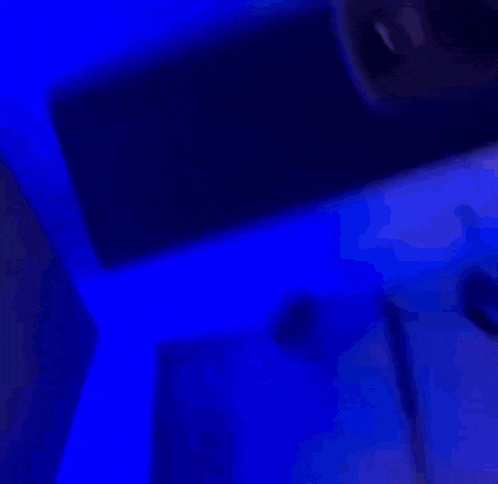a woman is laying on a bed in a dark room with a purple light behind her .