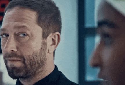 a man with a beard is standing next to another man in a room .