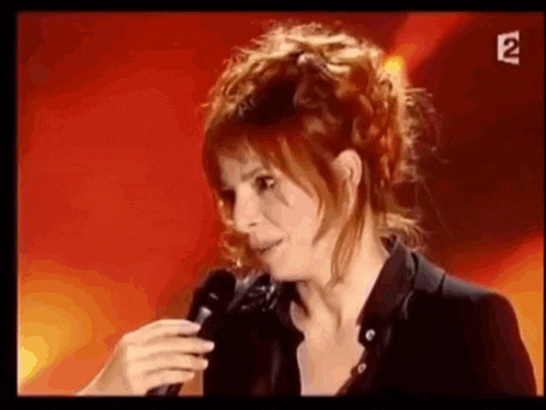 a woman is singing into a microphone on stage .