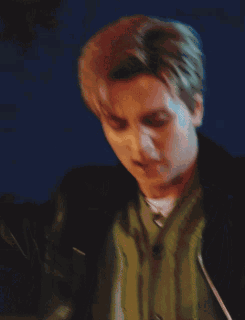 a man in a green shirt and a black jacket is looking down