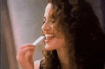 a woman with curly hair is eating a piece of chewing gum .
