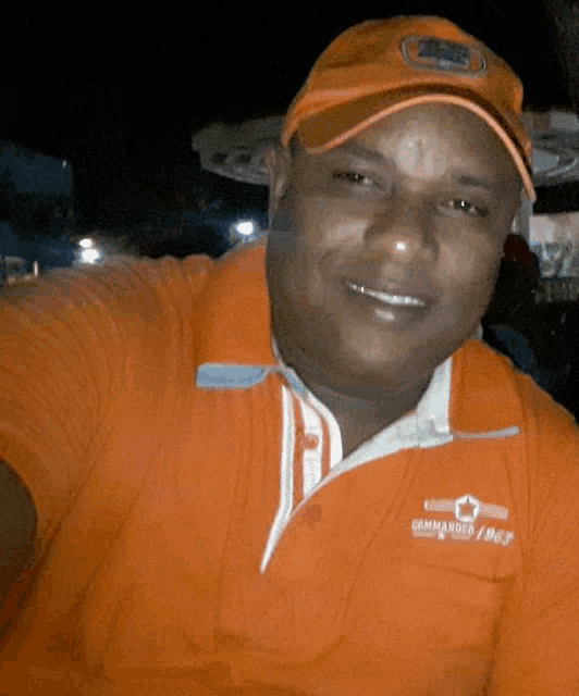 a man wearing an orange shirt that says commander 1967 smiles for the camera
