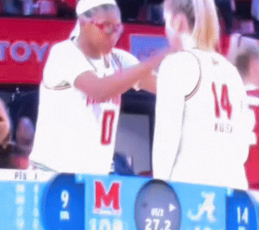 a basketball player with the number 14 on her jersey talks to another player