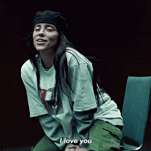 a woman wearing a t-shirt that says supreme on it sits in a chair and says i love you