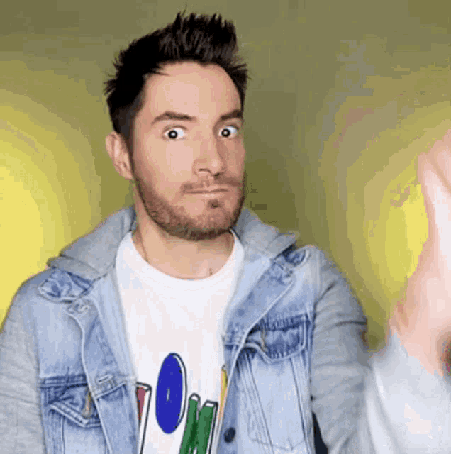 a man with a beard wearing a denim jacket and a t-shirt that says ' o ' on it