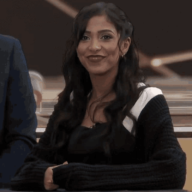 a woman in a black sweater is smiling and giving a middle finger