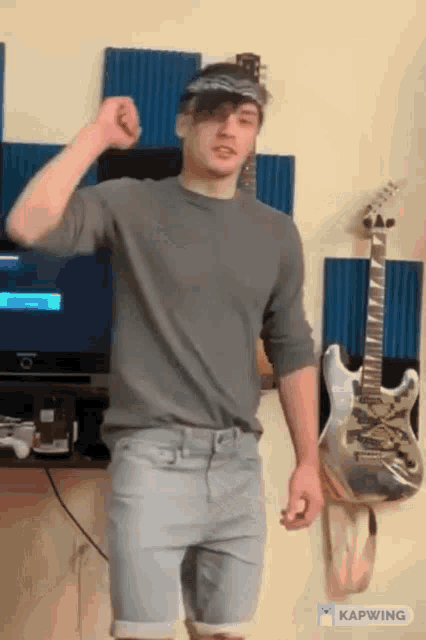 a man is dancing in front of a guitar and a tv ..