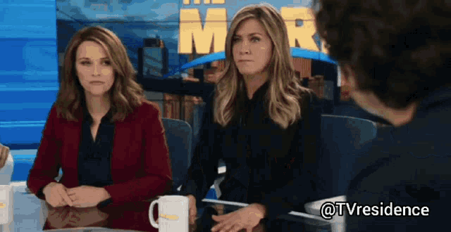 two women sit at a table with a man in front of a sign that says mr.