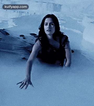 a woman is crawling out of a swimming pool .