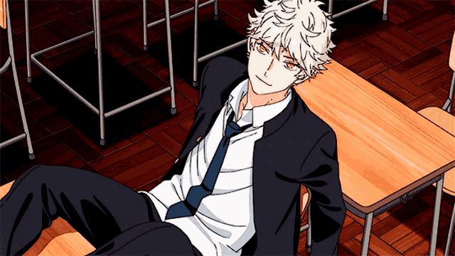 a boy in a suit and tie is laying on a desk