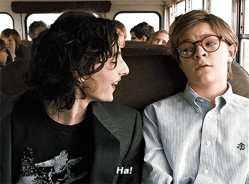 a boy and a woman are sitting on a bus and the boy is saying ha