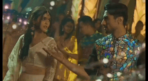 a man and a woman are dancing together at a party . the man is wearing a stained glass shirt .